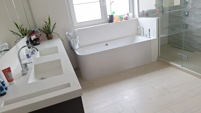 Lichte badkamer met bad, dubbele wastafel en douche