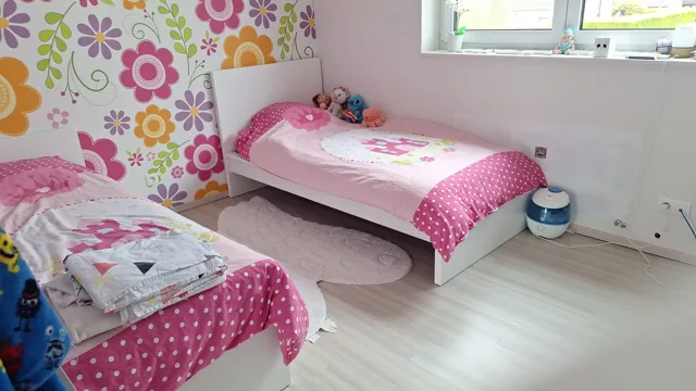 Overzicht van de kinderkamer met bedden en bloembehang