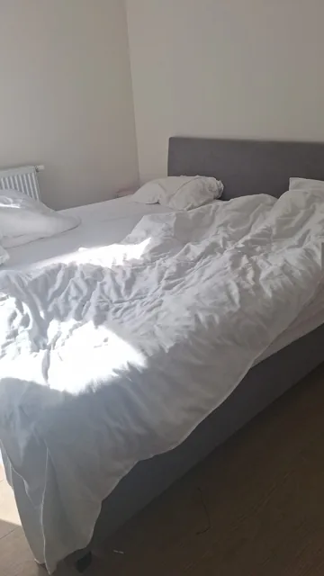 Overzicht van een slaapkamer met bed en nachtkastje