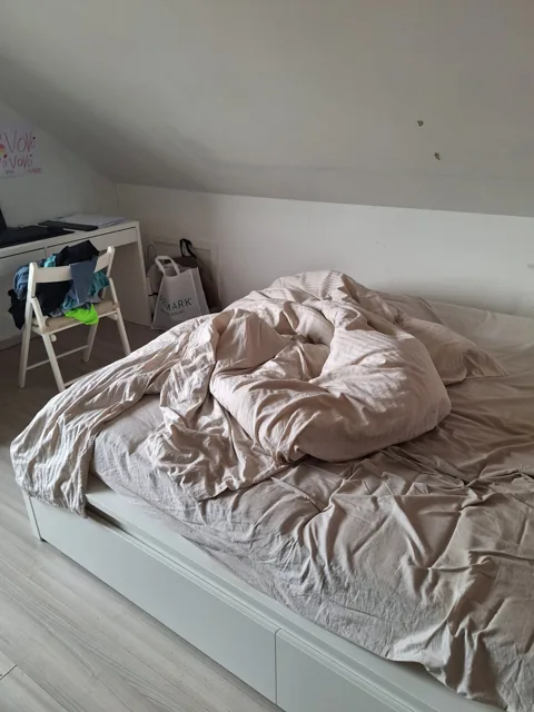 Bed en lichte vloer onder een schuin dak