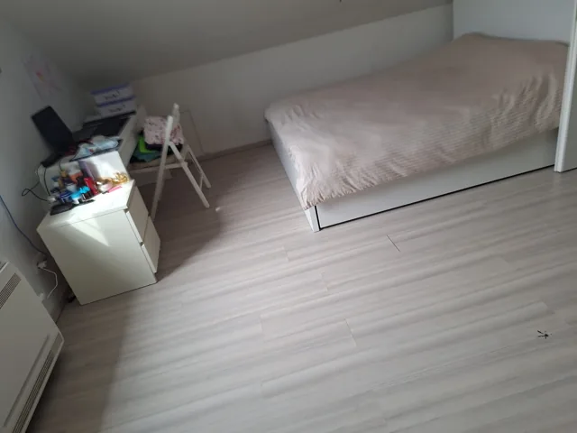 Zolderkamer met opgemaakt bed en nachtkastje