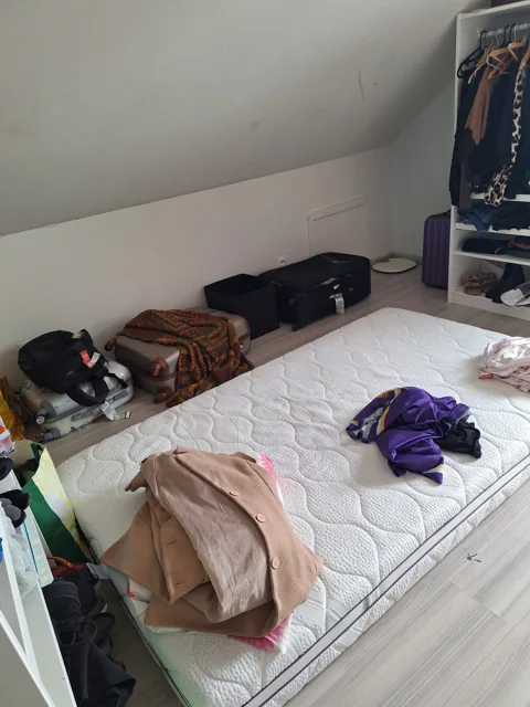Zolderkamer met bed en open kledingkast